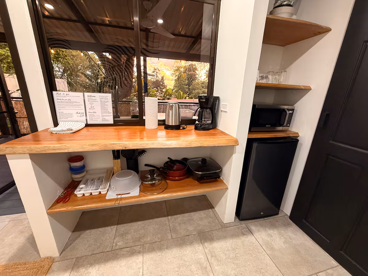 Kitchenette équipée avec mini-réfrigérateur, cafetière, bouilloire et accessoires de cuisine.