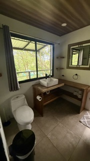 Salle de bain partagé de la villa de 6 chambres avec lavabo, toilette et vue sur la jungle tropicale du Costa Rica.