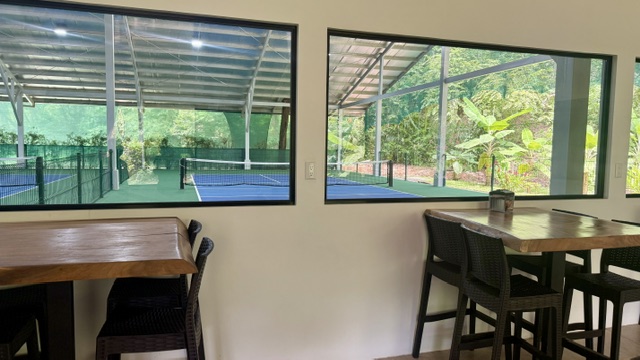 Espace climatisé avec grandes fenêtres donnant sur les terrains de pickleball du complexe à Uvita