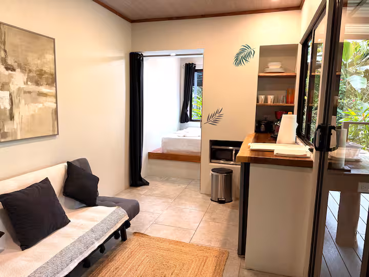 Salon avec canapé, télévision et kitchenette dans une villa de 2 chambres à Uvita.