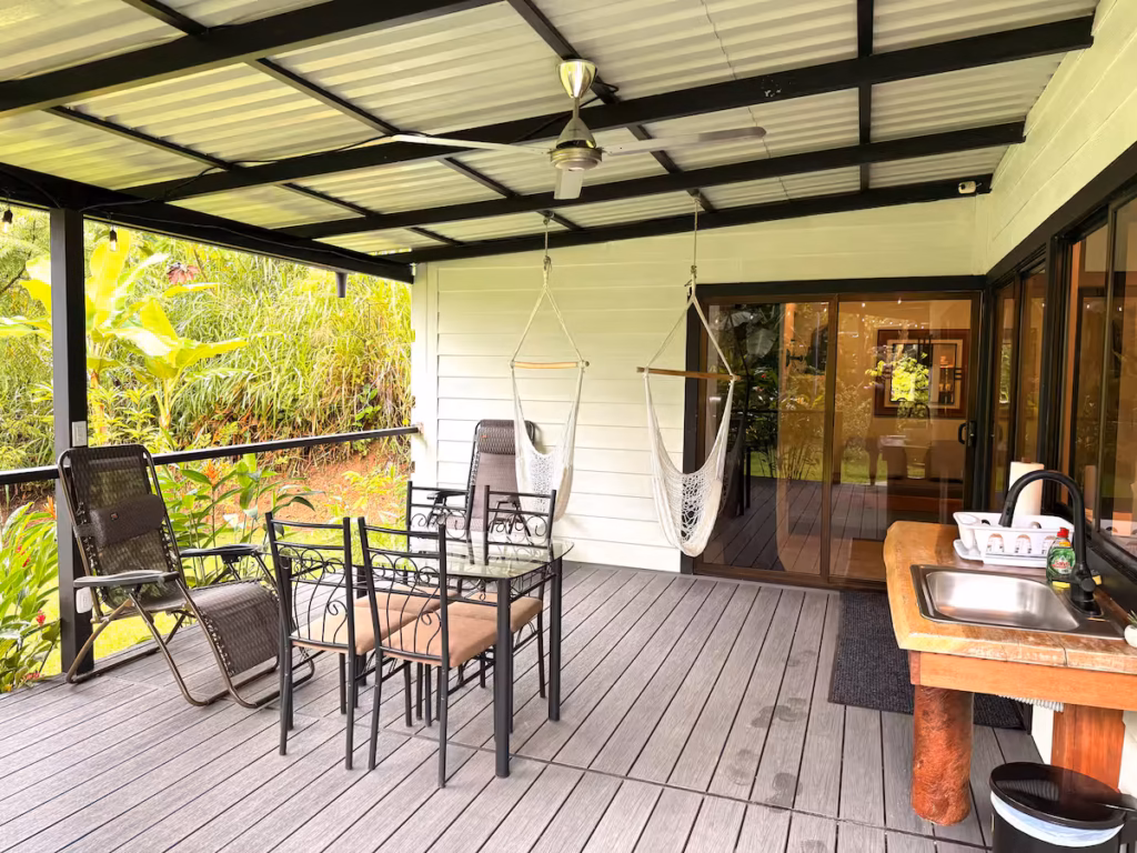 Terrasse couverte de la villa avec barbecue, espace repas et vue sur la nature tropicale.