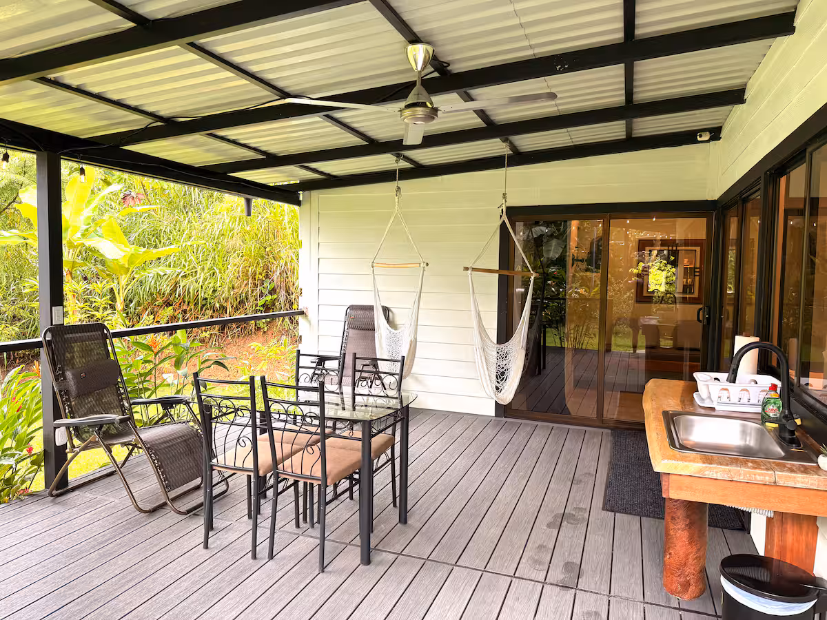 Terrasse couverte de la villa avec barbecue, espace repas et vue sur la nature tropicale.