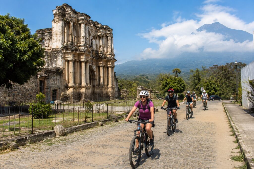 Excursion à vélo dans Antigua Guatemala devant les ruines coloniales et le volcan Agua lors du Circuit Guatemala divertissant.