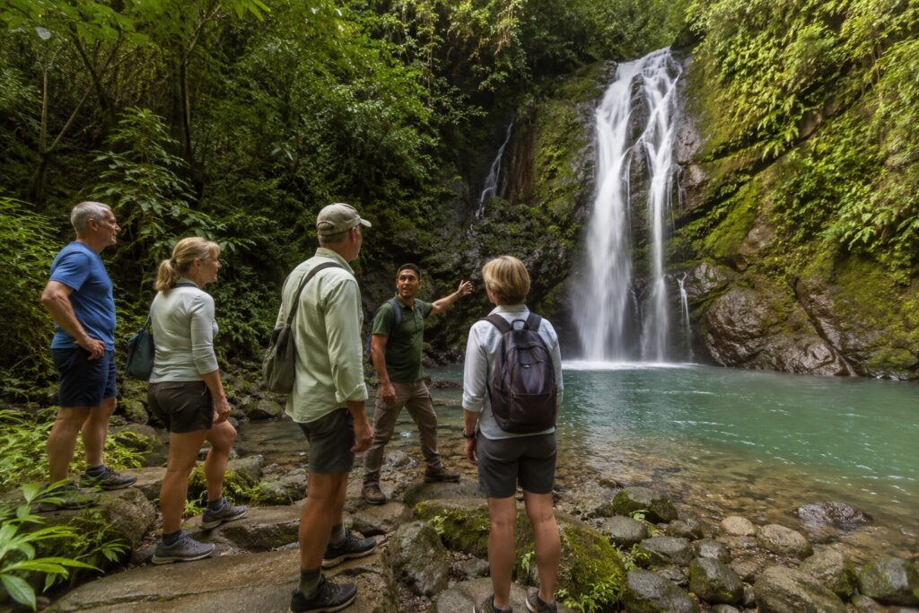 Voyageurs accompagnés d’un guide devant une cascade tropicale près de Jacó