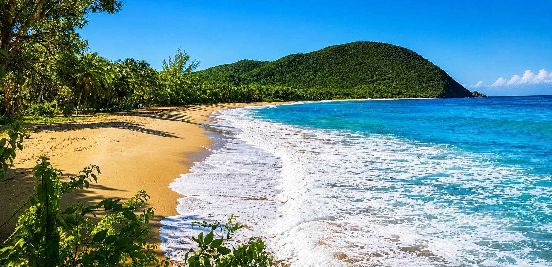 Plage tropicale de Deshaies en Guadeloupe avec sable doré et mer turquoise.