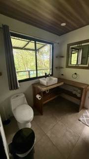 Salle de bain partagé de la villa de 6 chambres avec lavabo, toilette et vue sur la jungle tropicale du Costa Rica.