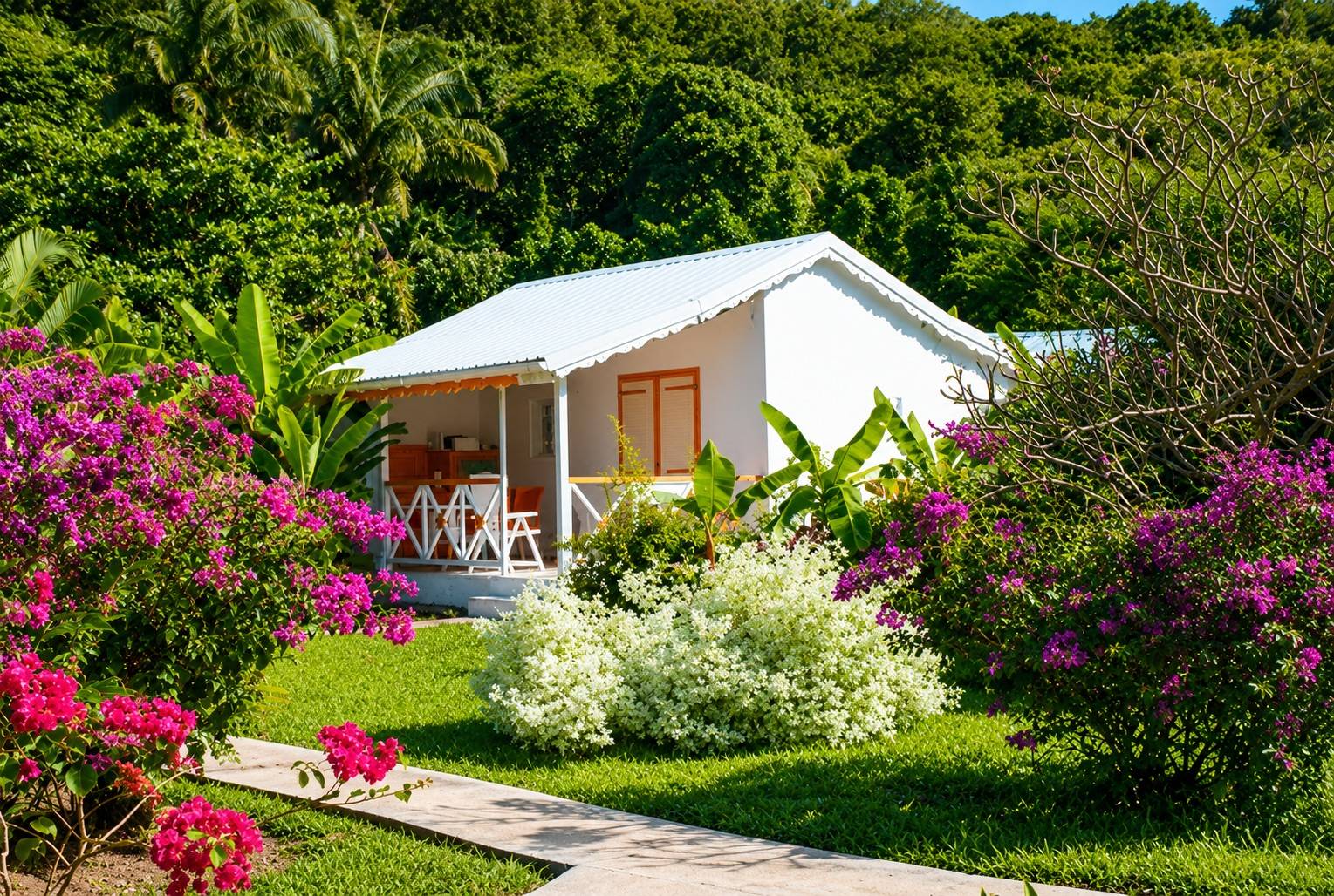 Bungalow créole avec terrasse et jardin tropical fleuri à Deshaies en Guadeloupe.