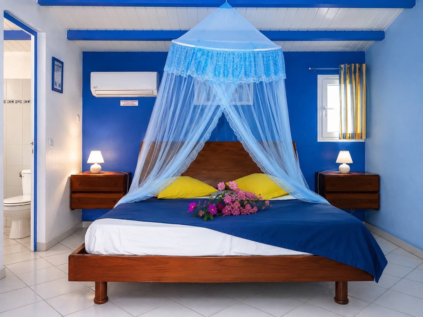 Chambre climatisée avec lit queen et moustiquaire dans un bungalow à Deshaies en Guadeloupe.